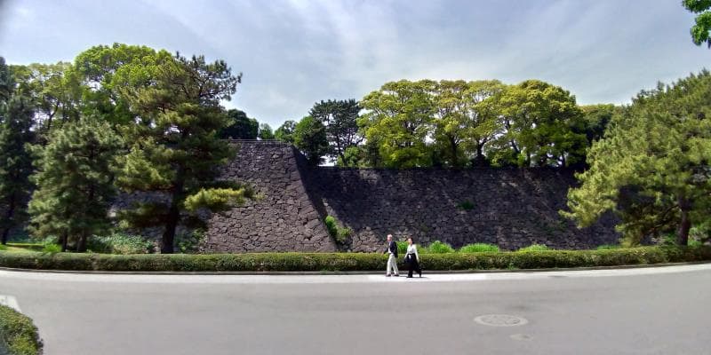 大きな石垣の前を散歩する夫婦