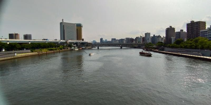 船が行き来する墨田川。左手に首都高、右手にはビル群